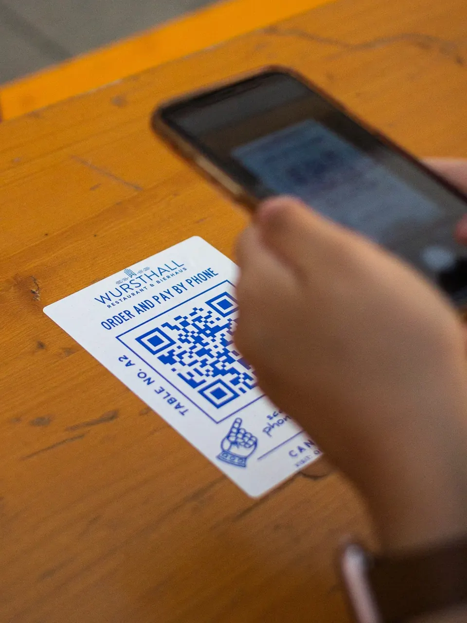 Una persona escanea con su teléfono el código QR de una mesa de restaurante